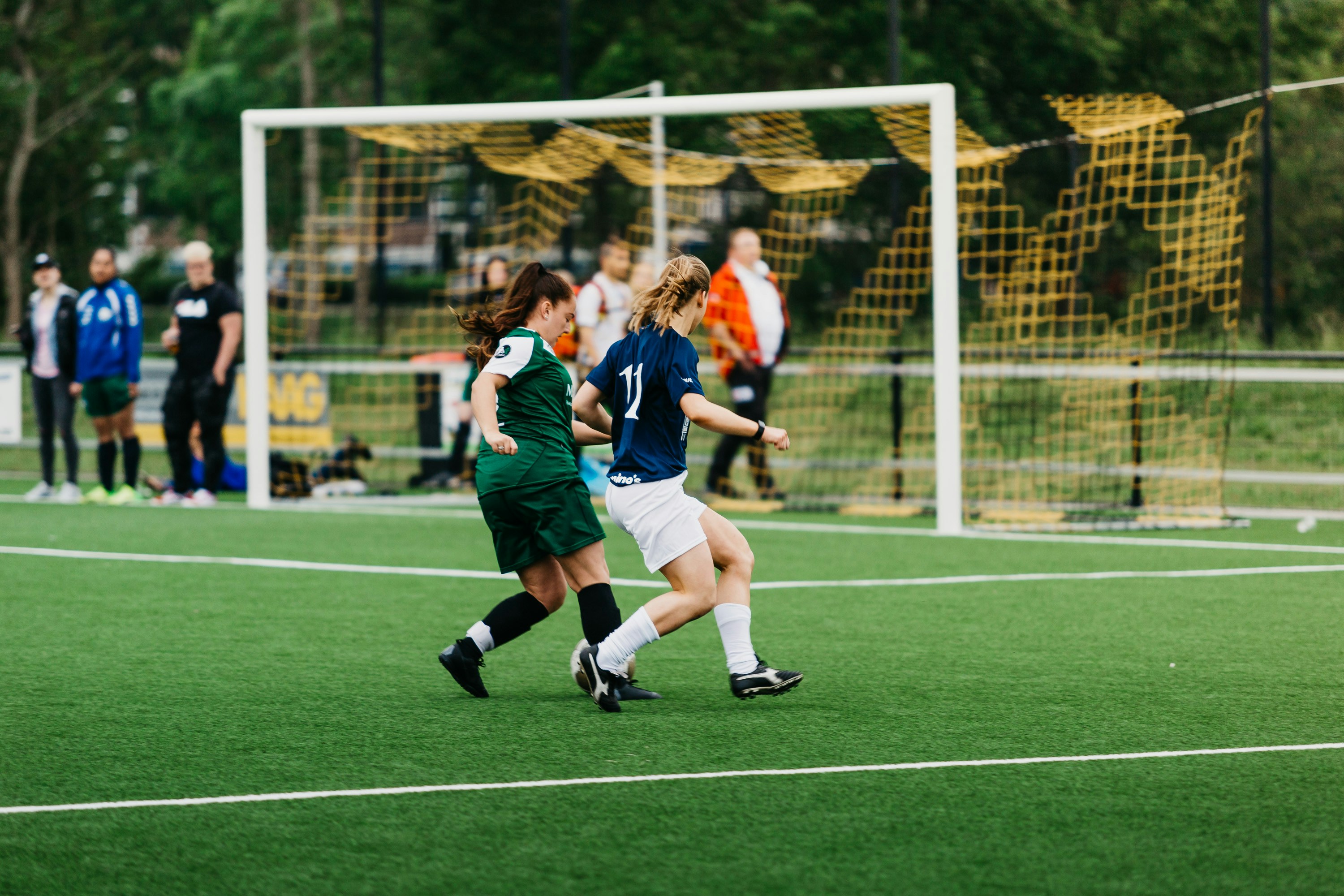 Kvinner spiller fotball på fotballbane.